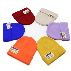 Winter knit beanies in multiple colors with vintage patches on a white background
