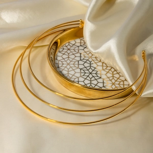 Macro shot of gold layered choker necklace on a silk cloth and patterned tray