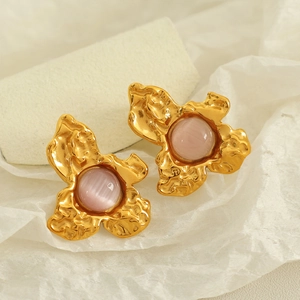 Modern gold floral stud earrings with pink cat-eye stones on textured paper