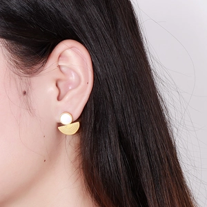 Modern gold semi-circle earrings with white round accent shown on model in a side view