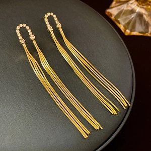Macro shot of gold tassel earrings with diamond accents and snake chain fringes