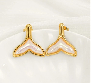 Détail de boucles d'oreilles queue de sirène dorées avec nacre sur support céramique