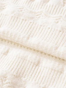 Macro shot of cream white chunky knit fabric with textured vertical stripes and waffle weave