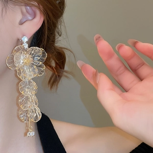 Close-up of acrylic flower tassel earrings with gold trim and crystal accents on a model