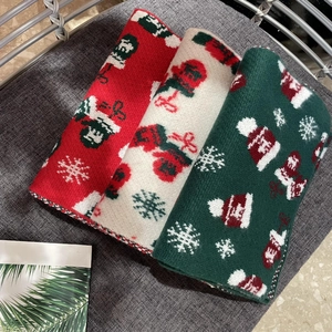 Close-up of three knitted Christmas scarves in red, white, and green with jacquard winter patterns