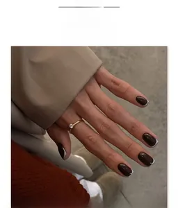 Faux ongles marron foncé style français avec pointes blanches et bague dorée