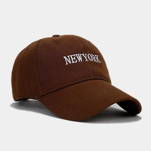Dettaglio del cappellino di cotone marrone con ricamo bianco della scritta NEW YORK