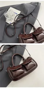 Detail of dark brown glossy leather saddle bag featuring dual front pockets and straps