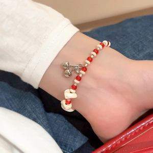 Detail of beaded bracelet with red transparent beads and a silver cherry pendant charm