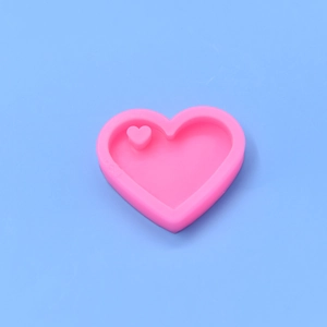 Pink heart-shaped silicone mold for DIY resin crafts and cake baking on blue background