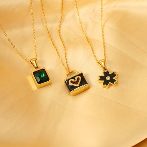 Three gold stainless steel necklaces with emerald, heart lock, and flower pendants