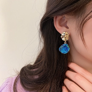 Close-up of blue textured round pendant earrings on model showing vintage gold details