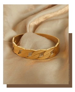 Detail view of gold titanium steel bangle featuring a classic Cuban link pattern design