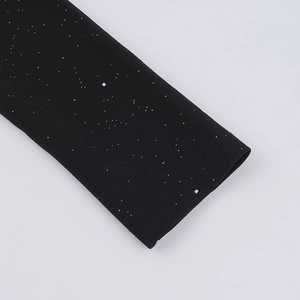 Detalle de la manga larga negra con tejido brillante de purpurina efecto estrellado