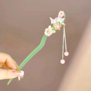 Macro detail of acetate floral hair stick with pink butterfly and beaded metal tassels