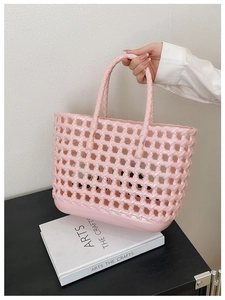 Detail of pink hollow woven jelly tote bag with glossy texture held by a model