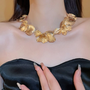 Detail of gold textured flower petal necklace on model with brushed metal finish