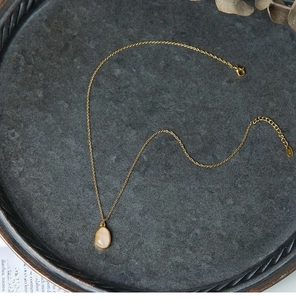 Detail of 18K gold-plated titanium necklace with oval green stone on stone tray