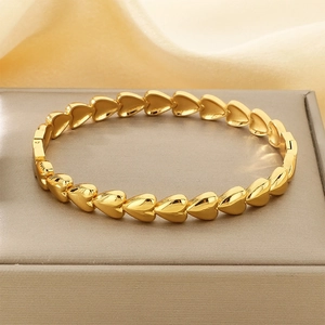 Detailed view of polished golden heart-shaped linked bangle on a luxury display box