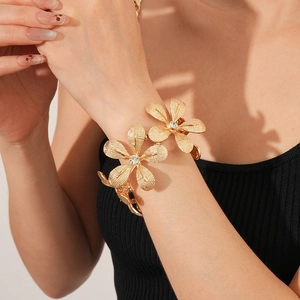 Detailaufnahme des goldenen Blumenarmbands mit Kristallinlay und gebürstetem Metall