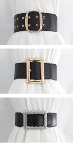 Detailed view of three vintage elastic waist belts with gold buckles on white outfits
