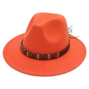 Detail of orange fedora hat featuring brown leather band with bronze metal shells