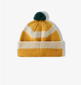 Detail van geel en wit gestreepte gebreide muts met groene pompon voor de winter