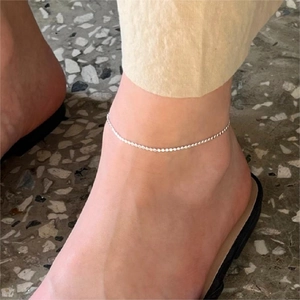 Minimalist S925 sterling silver anklet with flat beads worn on ankle over terrazzo