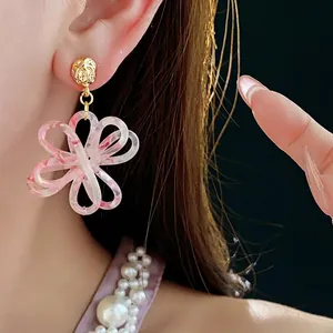 Elegant floral resin earrings with gold textured metal posts worn by a model