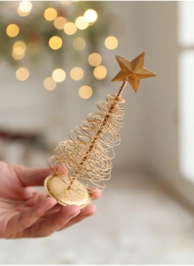 Golden spiral wire Christmas tree topper held in hand with mini star and glitter base