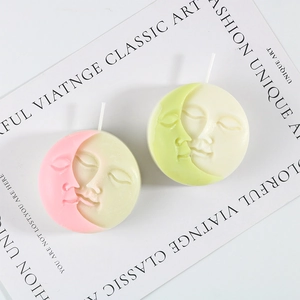 Detailed top view of 3D sun and moon face relief candles in pink and green art design