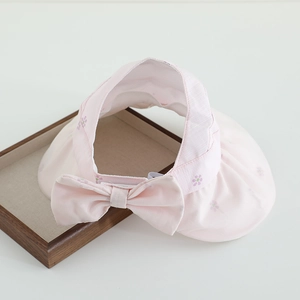 Detailed view of pink sun visor with large bow and purple floral print on brim