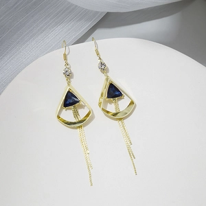 Macro shot of long golden tassel earrings with deep blue triangular gemstones and zircons