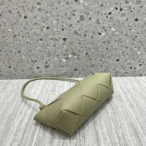 Detailed close-up of greyish-green woven leather shoulder bag with marble surface background