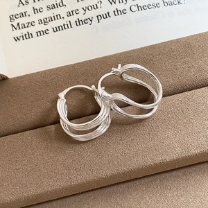 Close-up of silver hollow floral earrings with triple layered design on a jewelry stand