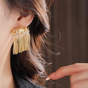 Gros plan de boucles d'oreilles pampilles dorées avec cristaux de zircon sur mannequin