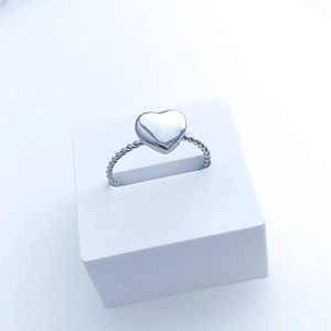 Detail of twisted silver stainless steel band featuring a polished heart-shaped center