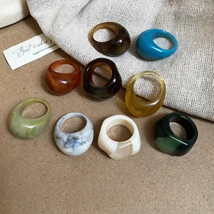 Collection of retro colorful resin oval rings on rustic linen and kraft background