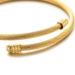 Macro detail of golden twisted stainless steel cable bracelet with spherical ball ends