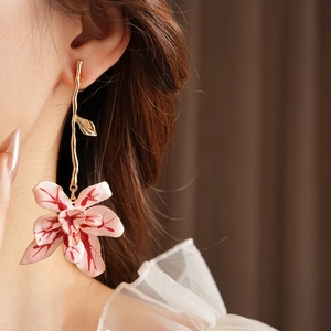 Close-up of vintage golden branch earring with pink enamel flower on a model