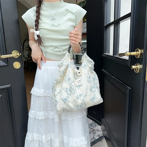 Detailed close-up of a cream canvas tote bag featuring blue butterfly print and soft texture