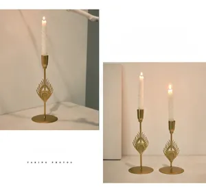Detail of Nordic gold metal candle holder featuring peacock feather carving and white candle