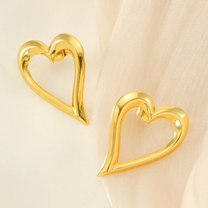 Orecchini a perno a cuore cavo in oro 18K su elegante sfondo di seta bianca liscia