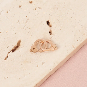 Macro detail of rose gold handcuff pendants on beige stone for jewelry making