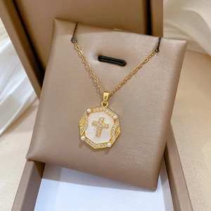 Detail of gold titanium necklace with shell octagonal pendant and crystal cross charm