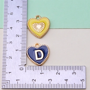 Detailed view of yellow and blue heart charms with size measurement on a metal ruler