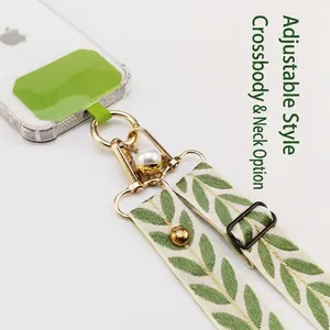 Adjustable crossbody phone strap with green leaf pattern, pearl charm and gold hardware