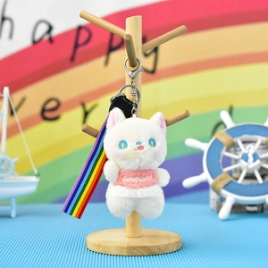 Close-up detail of a cute white plush cat keychain featuring a lace skirt and rainbow strap