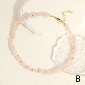 Macro detail of rose quartz stone necklace with golden spacer beads and lobster clasp