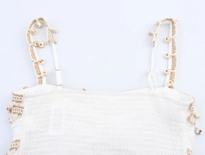 Detailed close-up of bohemian crop top with woven straps and natural shell ornaments